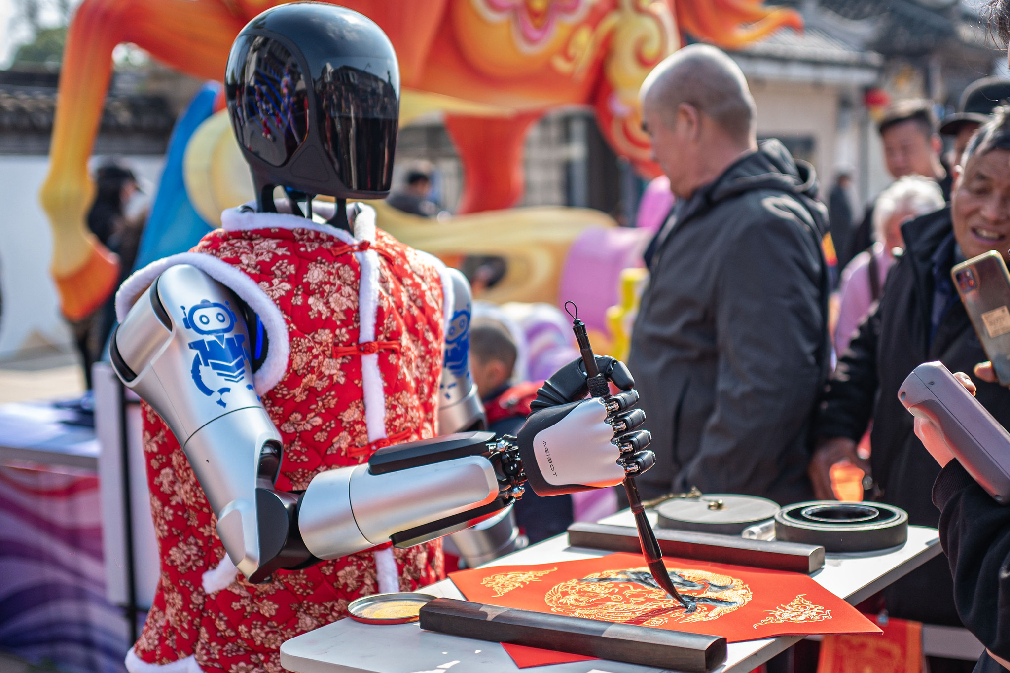 Humanoid robots take up brushes to write Chinese calligraphy at the ancient town of Zhouzhuang in Kunshan, east China's Jiangsu Province, on February 17, 2026. /VCG