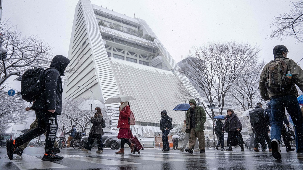 People cross a street during a snowfall in Tokyo, Japan, February 8, 2026. /VCG