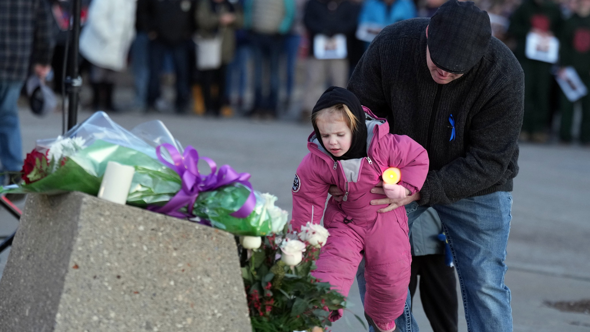 A child lays flowers at a vigil for the victims of a mass shooting, in Tumbler Ridge, B.C., Canada, February 13, 2026. /VCG