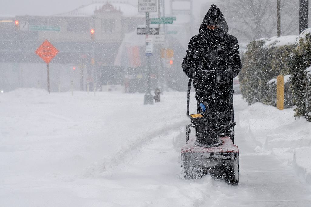 A person works to clean the sidewalk during a snow storm in the Bronx borough of New York City, January 25, 2026. /VCG