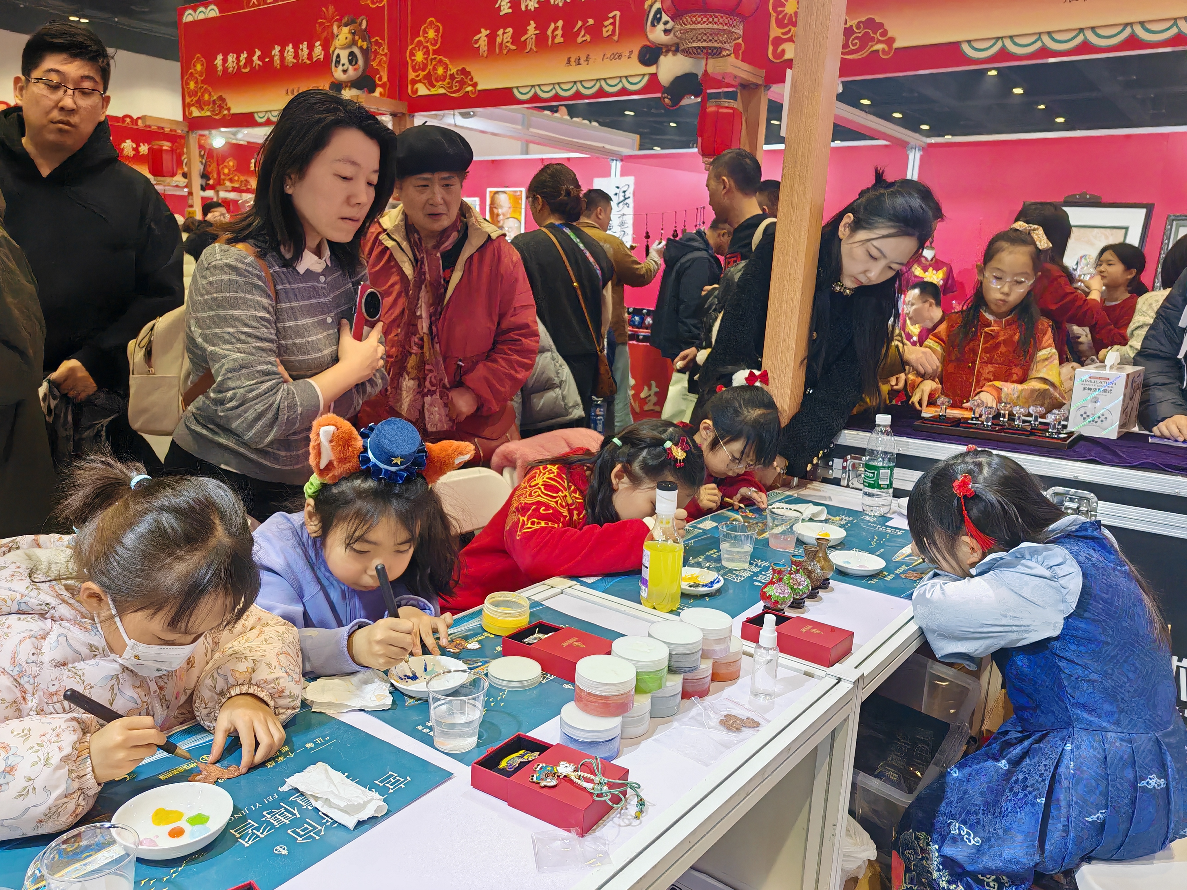 Parents and their children experience cloisonne-making techniques at an indoor temple fair in Beijing on February 23, 2026. /CGTN