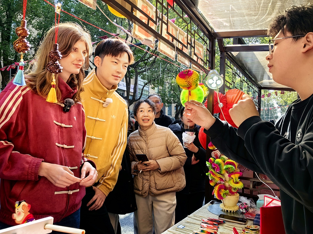 Foreign students experience the intangible cultural heritage of fan-fold paper art at the first Spring Festival Market on University Road in Wujiaochang, Shanghai, China, February 18, 2026. /VCG
