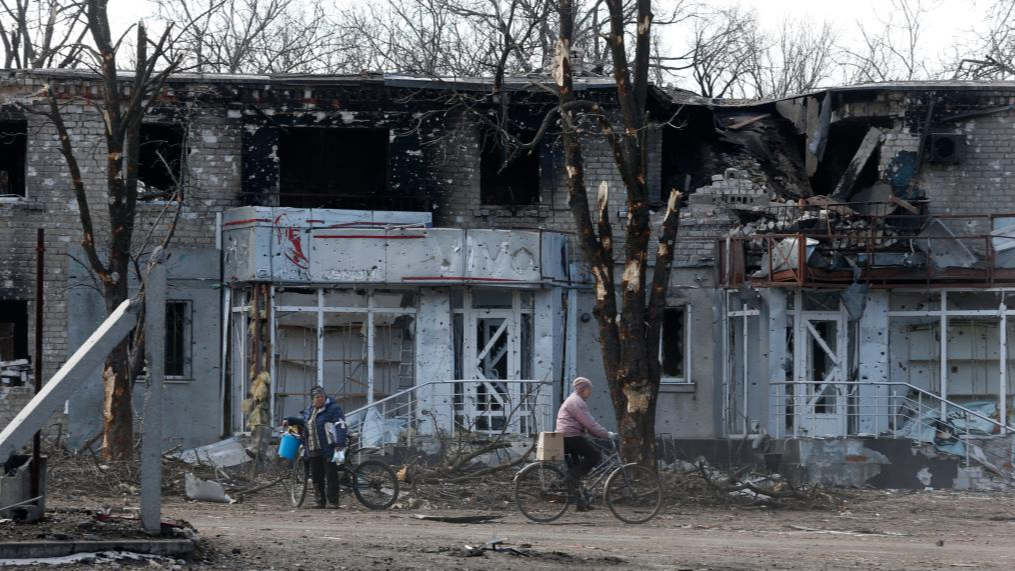 Local residents are seen outside a damaged building in Volnovakha of Donetsk, March 15, 2022. /Xinhua