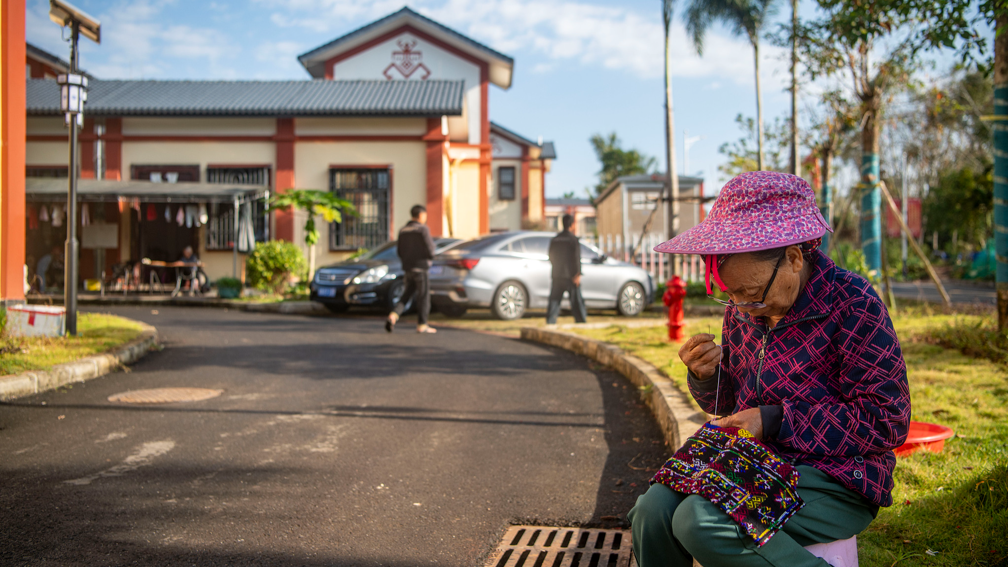 A villager from Miantou is weaving Miao embroidery at the entrance of her village, in Qionghai, Hainan Province, south China, February 11, 2026. /CFP