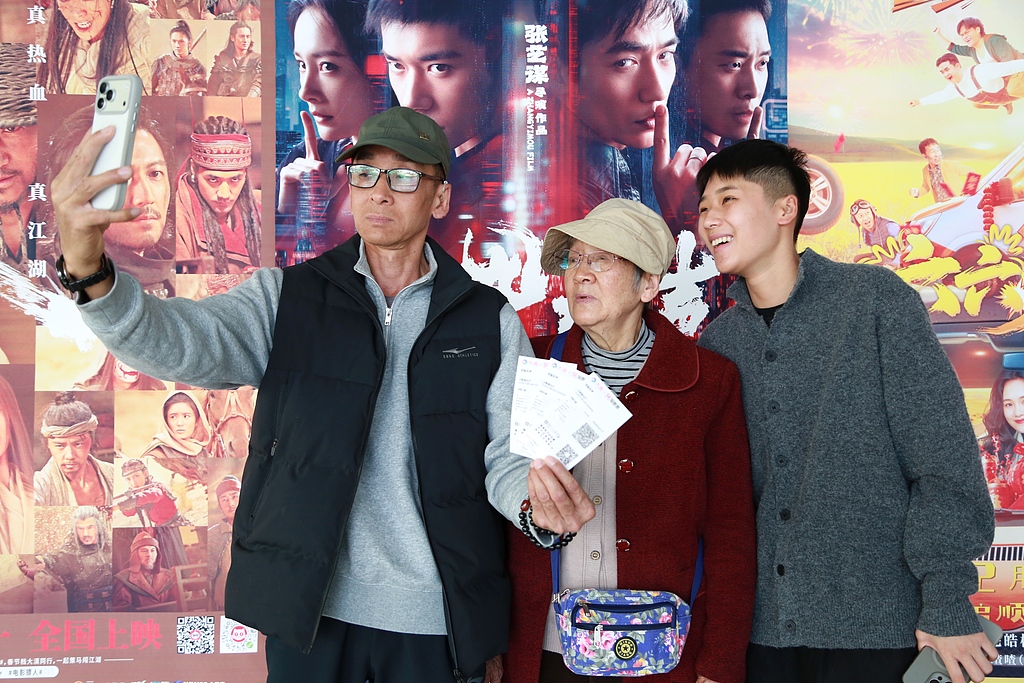 Three generations of a family take a selfie in front of movie posters at a cinema in Mengzi, Yunnan Province, on February 17, 2026. /VCG