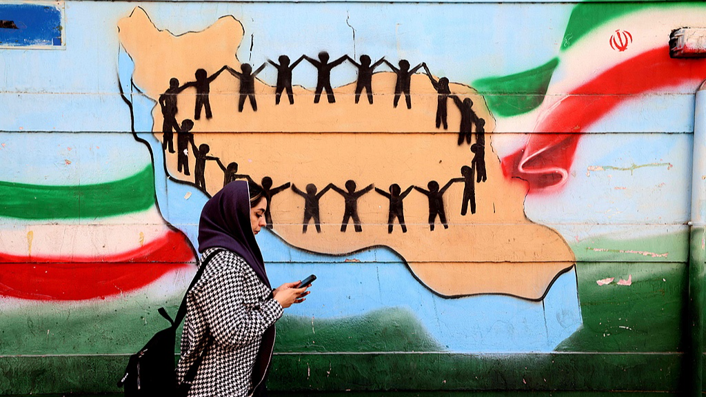A woman walks past the flag and map of Iran painted on a wall in Tehran, Iran, February 25, 2026. /VCG