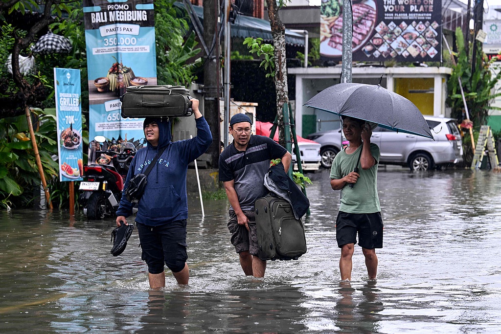 Hotel guests wade through flooded streets in Legian, Kuta, near Denpasar, Bali, Indonesia, after torrential rains triggered flooding. February 24, 2026. /CFP