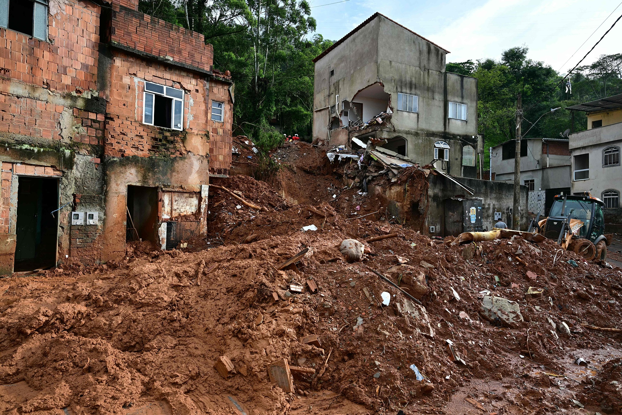A backhoe loader clears mud and debris in Juiz de Fora, Minas Gerais state, Brazil, February 26, 2026. /VCG