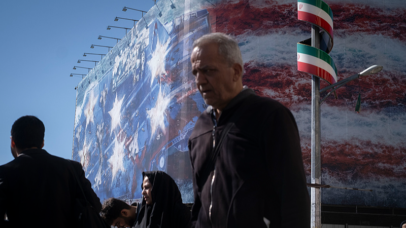 Iranian people walk through the area under a state building covered with a giant anti-U.S. billboard in Tehran, Iran, February 26, 2026. /VCG
