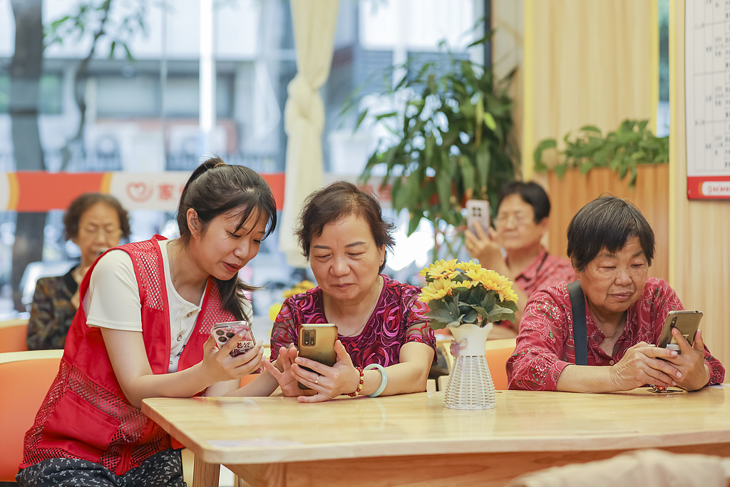 Volunteers teach seniors how to use smartphones at a community senior care service center in Fuzhou City, east China's Fujian Province. /VCG