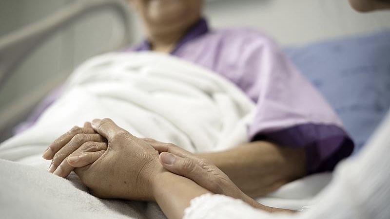 A hospital companion comforts a hospitalized patient, sitting by the bedside to provide reassurance and a sense of security. /CMG