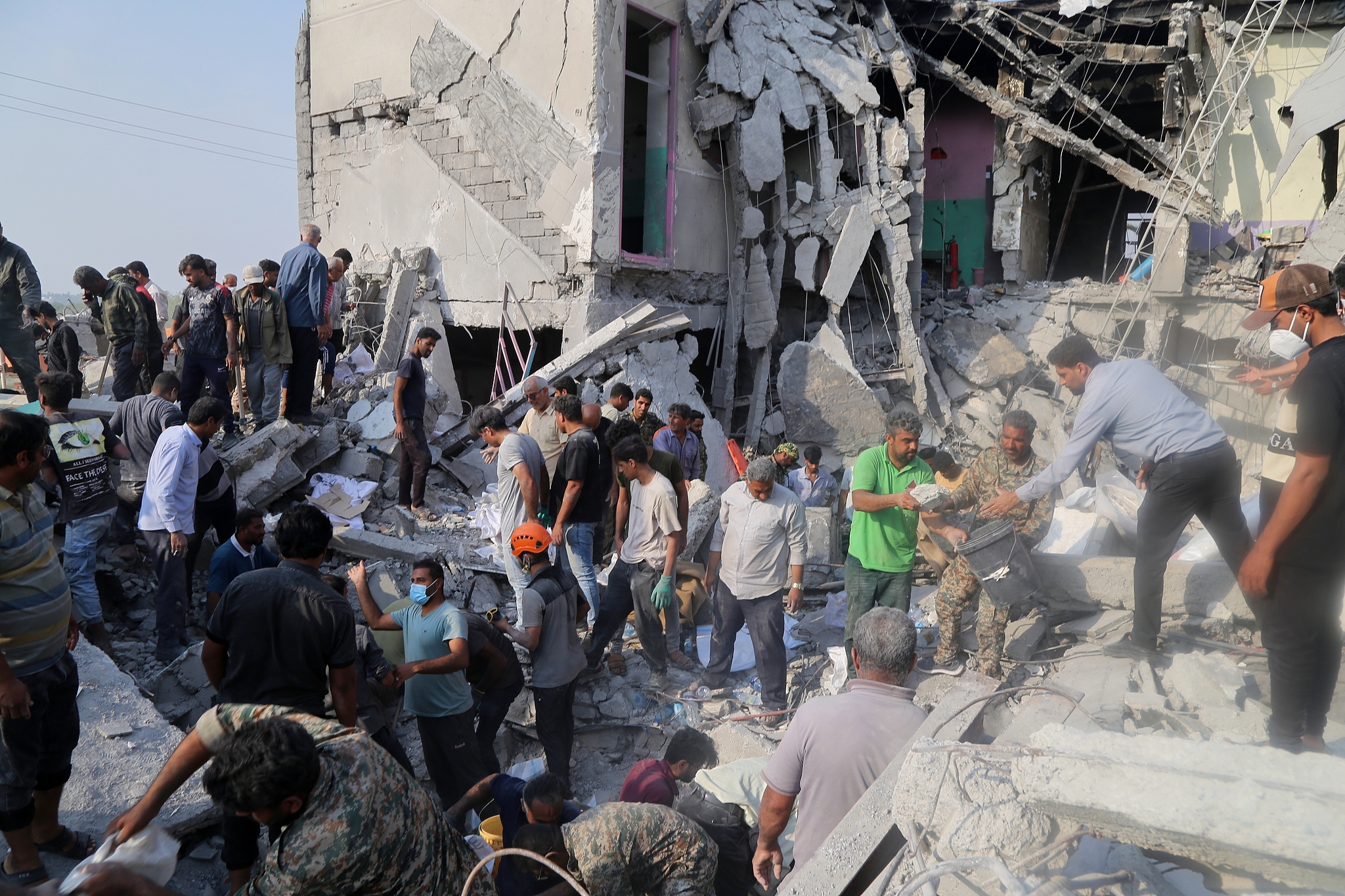 Rescue workers and residents search through the rubble in the aftermath of a US-Israeli strike on a girls' elementary school in Minab, Iran, February 28, 2026. / CFP
