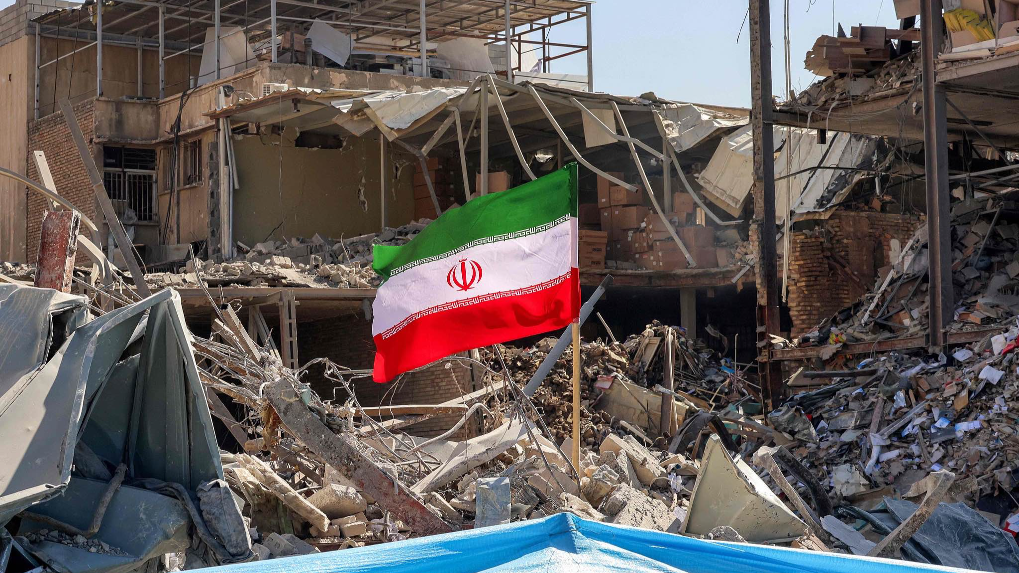 An Iranian flag is placed in the rubble and debris next to a destroyed residential building near Ferdowsi Square in Tehran, capital of Iran, March 3, 2026. /CFP