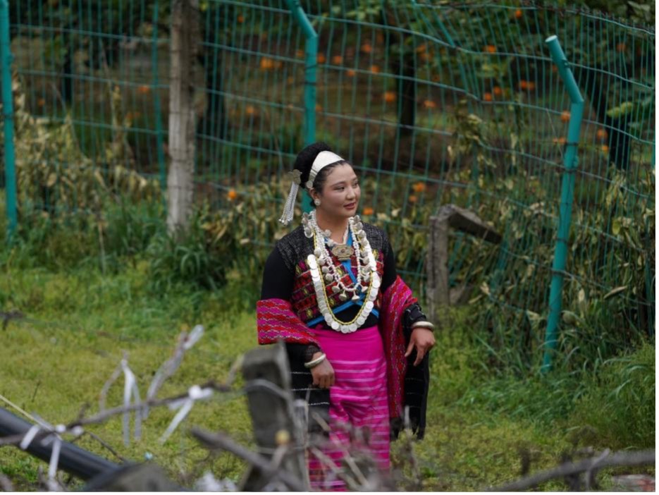 A woman walks through a citrus orchard in a Deng resettlement village, Zayu County, Nyingchi City, Xizang. /CGTN