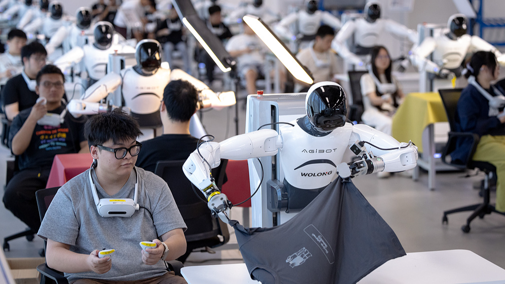 Humanoid robots follow technicians to learn various job skills in Shaoxing, Zhejiang province, China, 14 September 2025./VCG