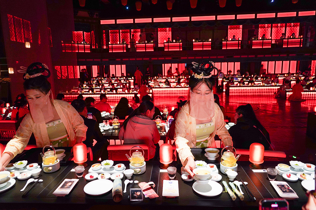 Staff dressed in Song Dynasty attire serve dishes at the Qingming Riverside Landscape Garden in Kaifeng, Henan Province, on September 26, 2025. /VCG