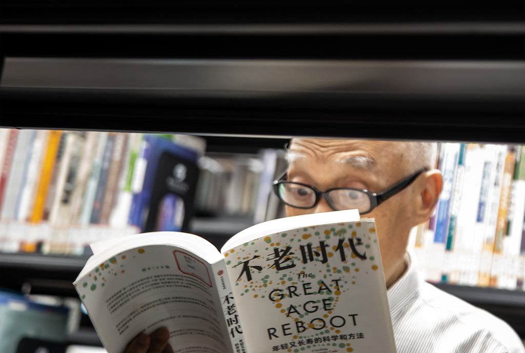 A senior enjoys reading at a local bookstore in Fuzhou, Fujian Province on October 4, 2024. /VCG