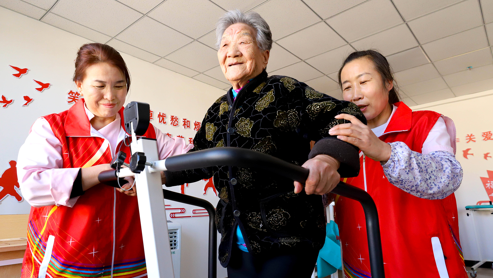 Volunteers help an elder do exercise at a nursing home in Zhangye City, northwest China's Gansu Province, March 5, 2026. /VCG