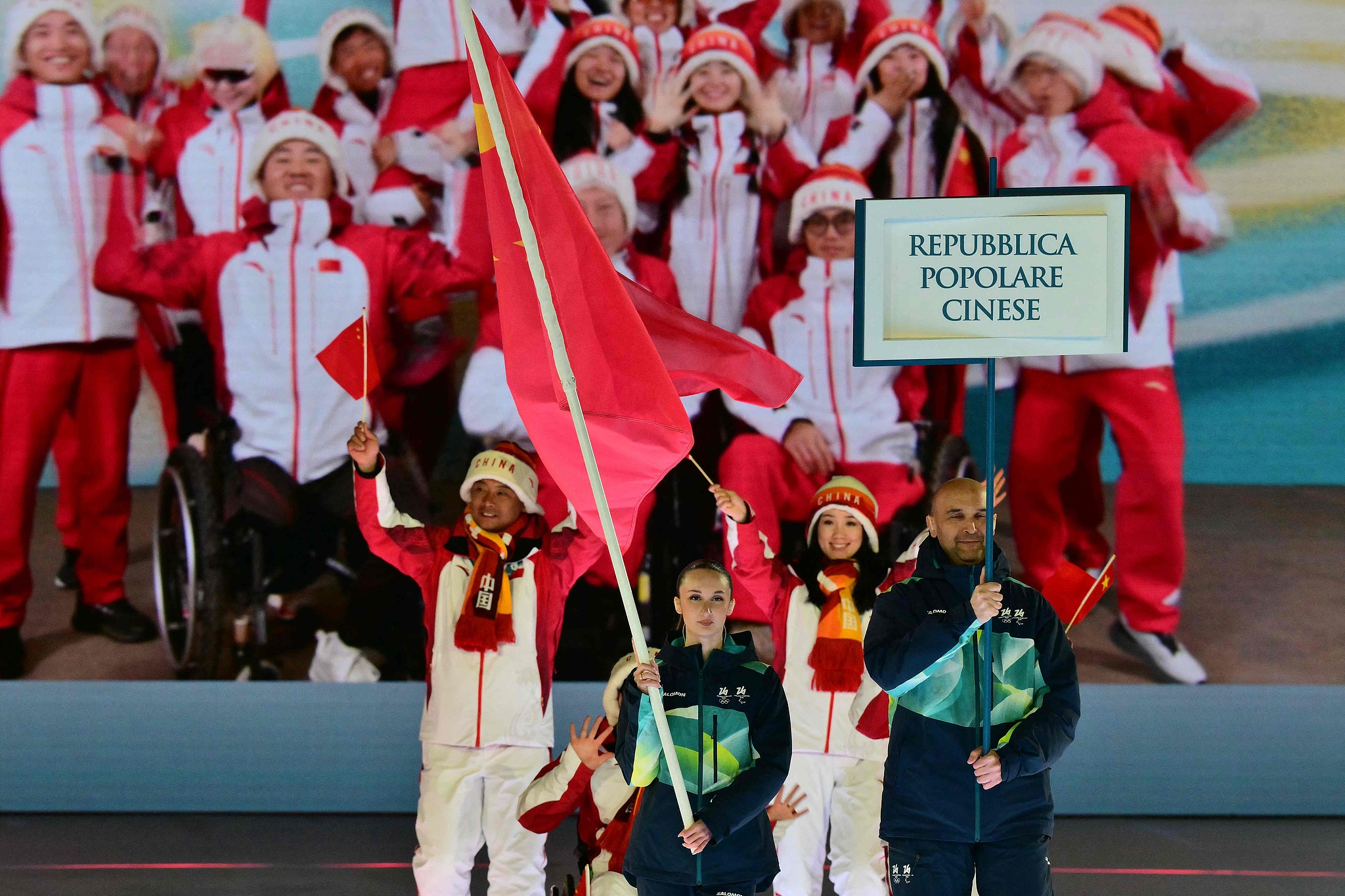Members of China's delegation parade as volunteers hold a flag and a placard during the delegation parade of the Milano Cortina 2026 Winter Paralympic Games opening ceremony at Arena di Verona in Verona, Italy, March 6, 2026. /VCG