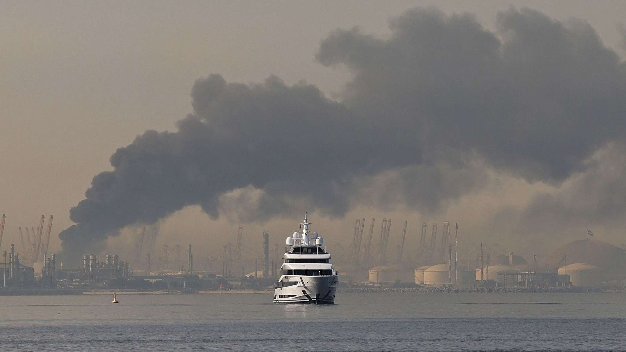 A ship sails past a plume of smoke rising from the port of Jebel Ali following a reported Iranian strike in Dubai, UAE, March 1, 2026. /VCG