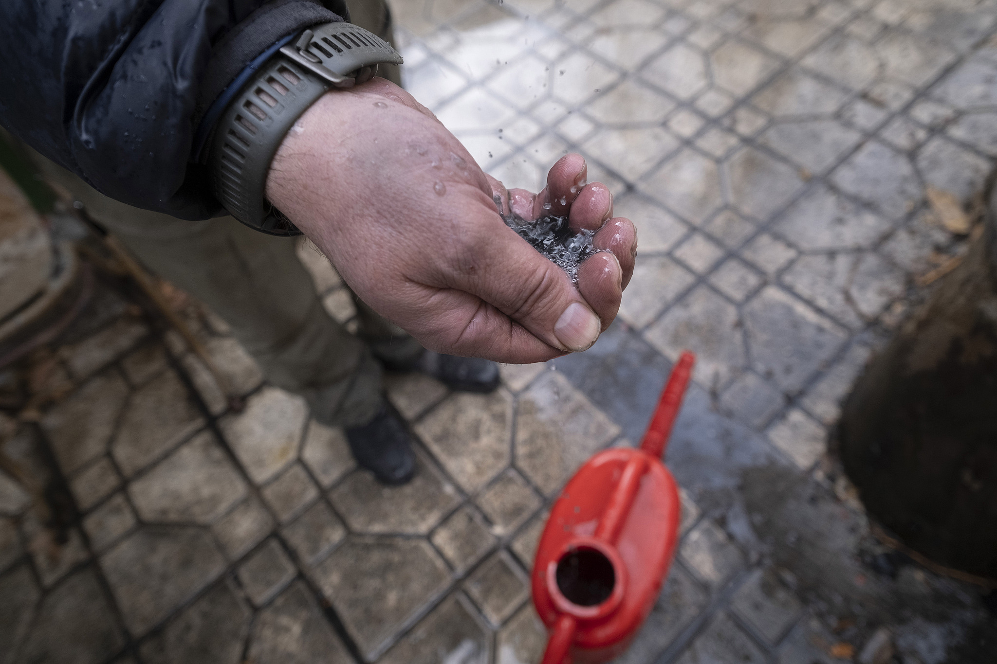 An Iranian man tries to show dark water polluted by oil-soot residue from Tehran's petroleum storage facilities, which are struck during US-Israeli military strikes, Tehran, Iran, March 8, 2026. /VCG