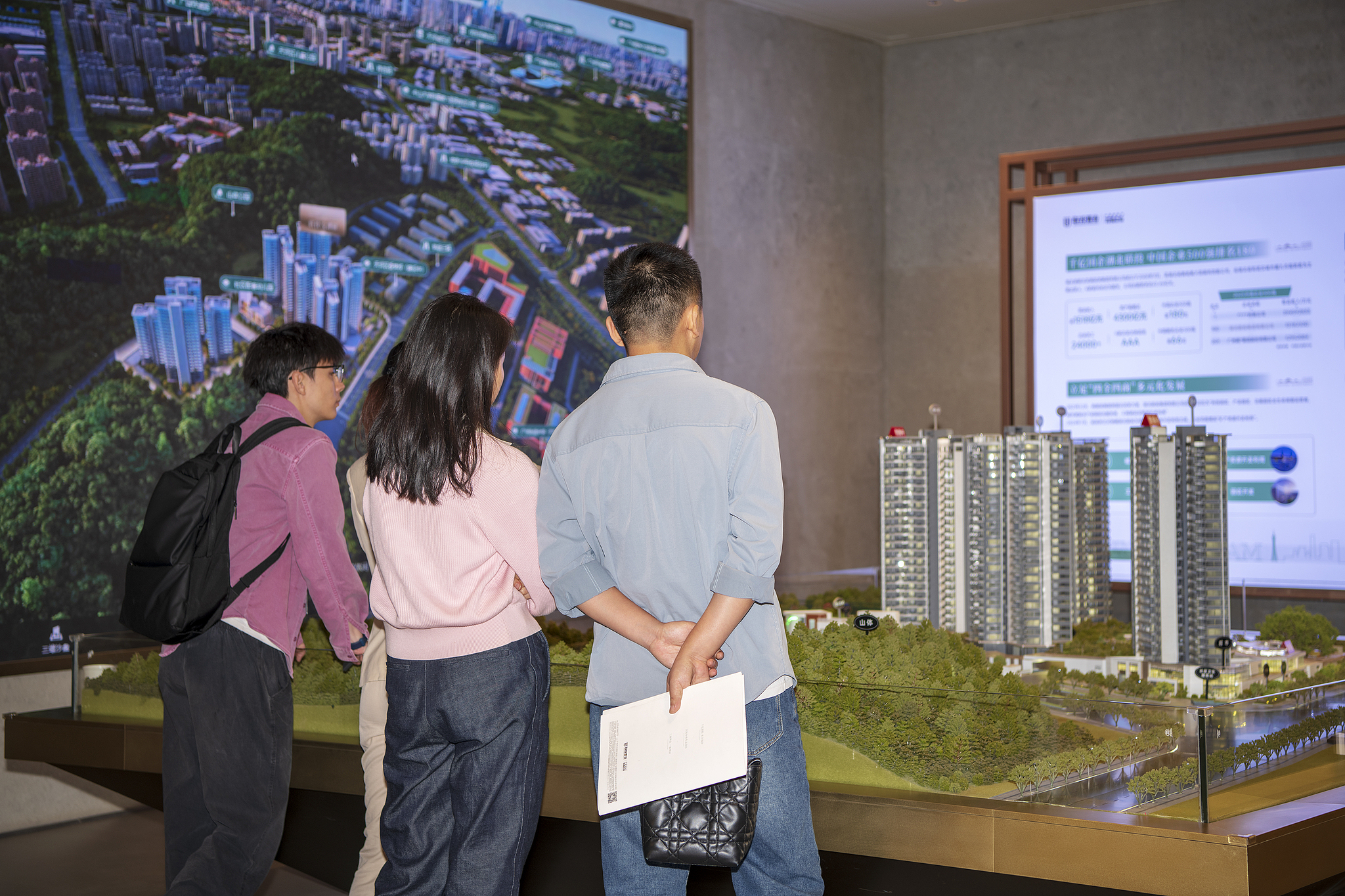 People inspect the model of a residential project. /VCG