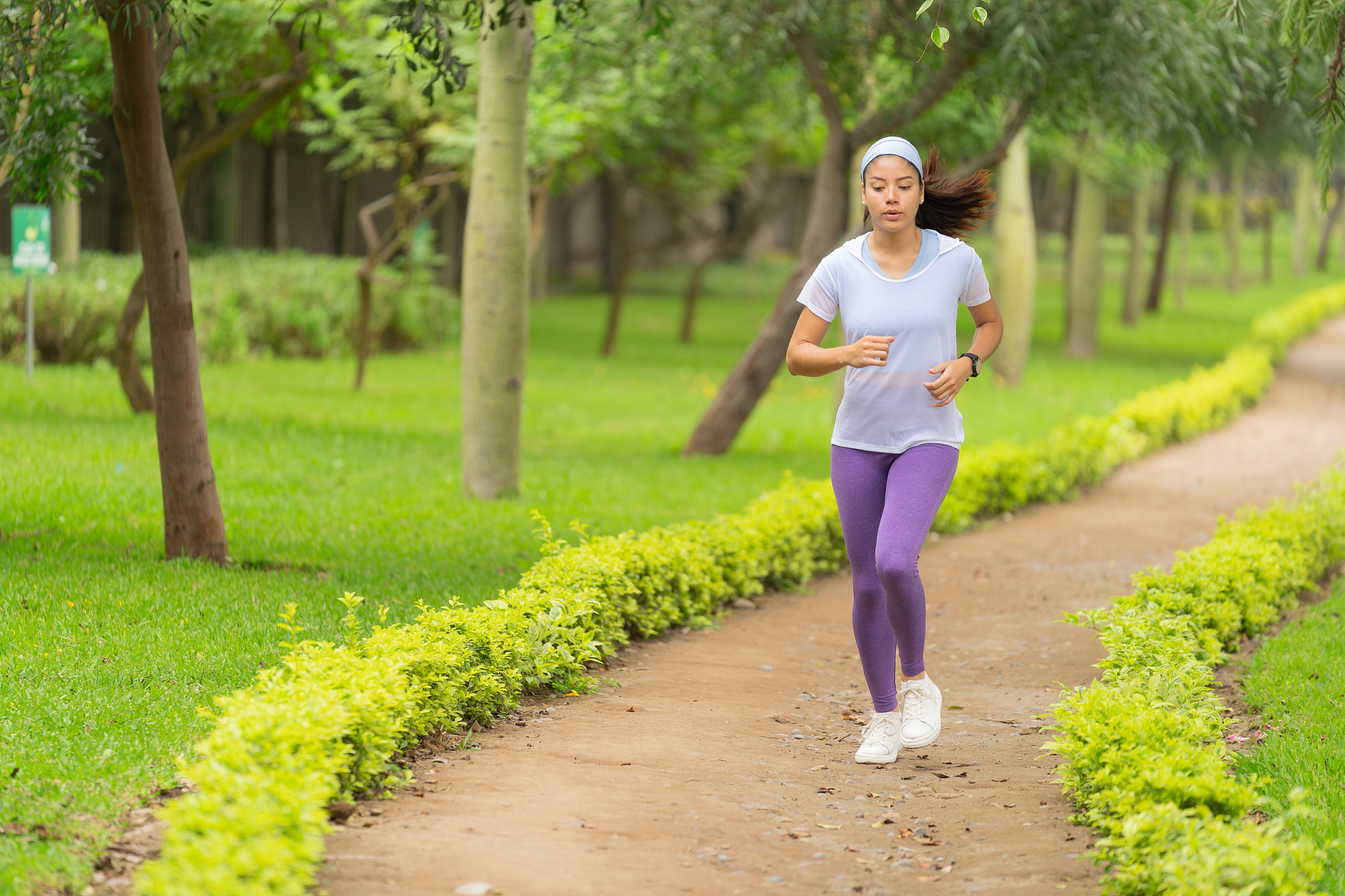 A woman running alone along a park pathway. /VCG