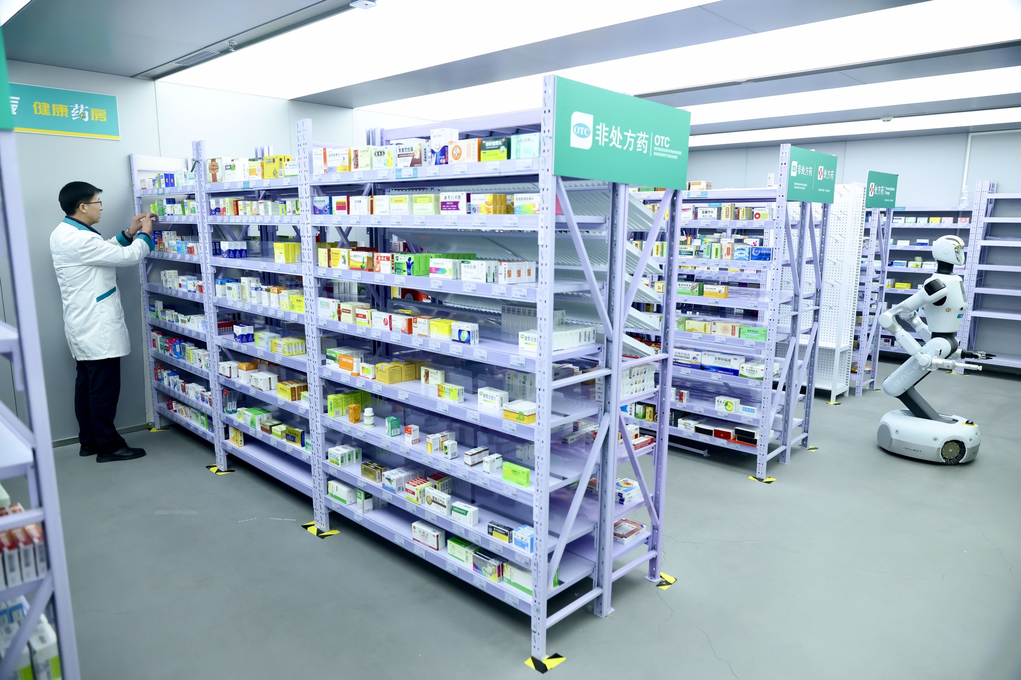 The intelligent pharmacy robot works in a drugstore in Beijing's Haidian District, assisting a pharmacist in handling medicines, March 12, 2026. /VCG