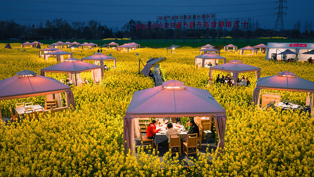 People enjoy Sichuan hotpot in a rapeseed flower field in Chongzhou, Sichuan Province on March 5, 2026. /VCG