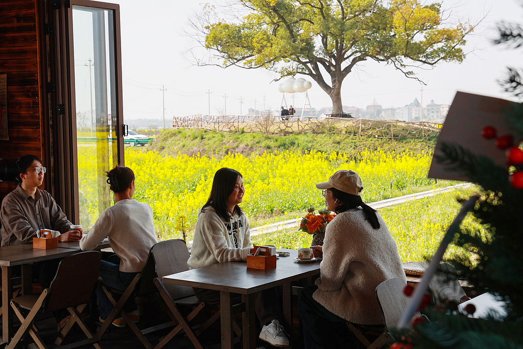 Visitors sip coffee and enjoy blooming rapeseed fields in Jinhua, Zhejiang Province on March 10, 2026. /VCG
