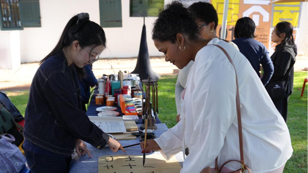 A woman learns Chinese calligraphy at the 2025 International Chinese Language Day event in Cape Town, South Africa, April 17, 2025. /Xinhua