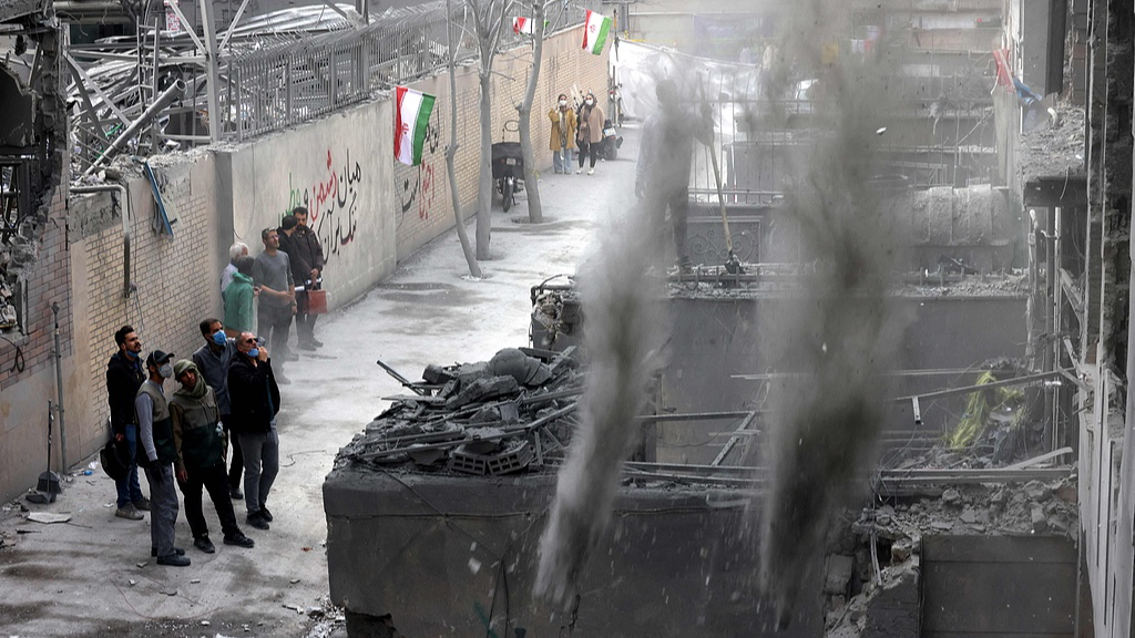 Iranian residents look on as debris is cleared from a damaged building in Tehran, capital of Iran, March 15, 2026. /VCG