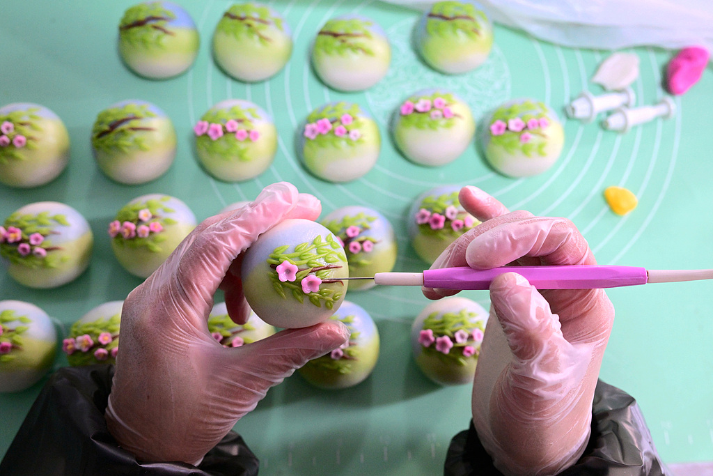 A dumpling maker shapes delicate floral designs on Qingming Guo at Wang Lijuan’s workshop in Jinhua, Zhejiang Province, China. /VCG