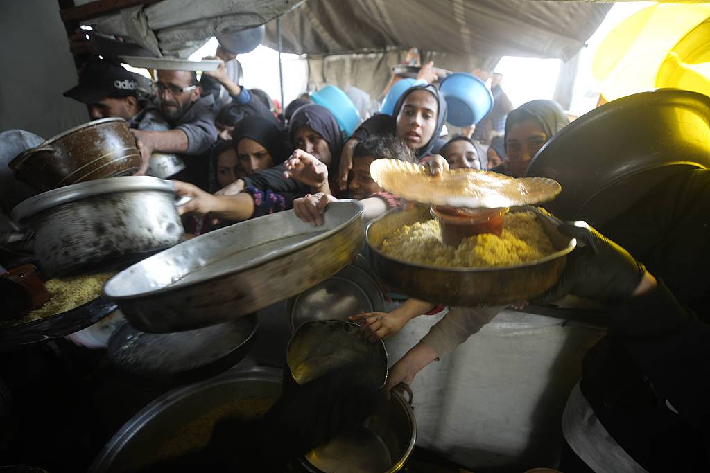 Displaced Palestinians gather to receive meals from a charity kitchen during Ramadan in Gaza City, March 15, 2026. /VCG