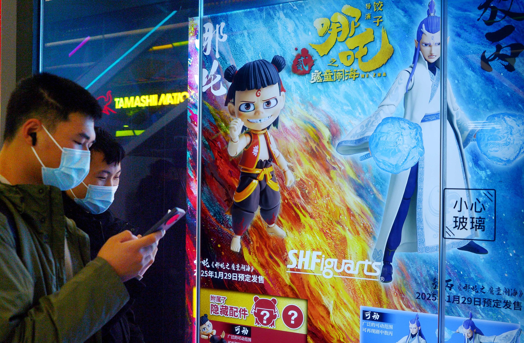 Young visitors stand in front of a Ne Zha poster, browsing information on film-related merchandise, Shanghai, China. /VCG