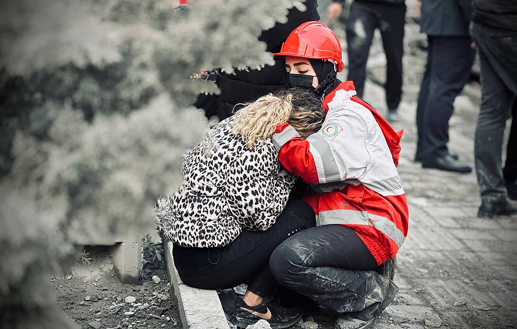 Rescue workers from the Iranian Red Crescent assist an injured woman after a US-Israeli air strike targeted a residential building in central Tehran, Iran, March 17, 2026. /VCG