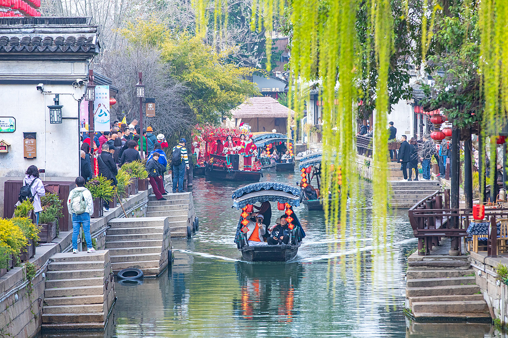 Boats slide through canals as visitors fill the narrow streets in Nanxun Ancient Town of Huzhou, Zhejiang Province on March 19, 2026. /VCG