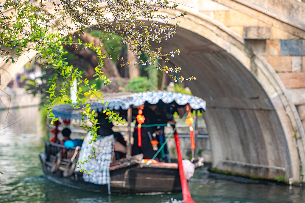 Boats slide through canals as visitors fill the narrow streets in Nanxun Ancient Town of Huzhou, Zhejiang Province on March 19, 2026. /VCG