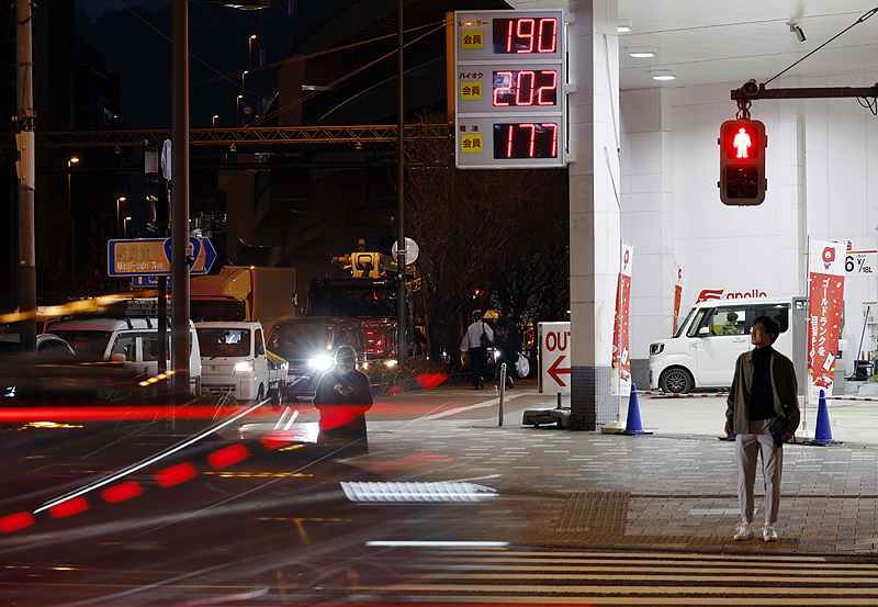 A pedestrian waits at a traffic light in front of a gas station in Tokyo, Japan, March 18, 2026./VCG