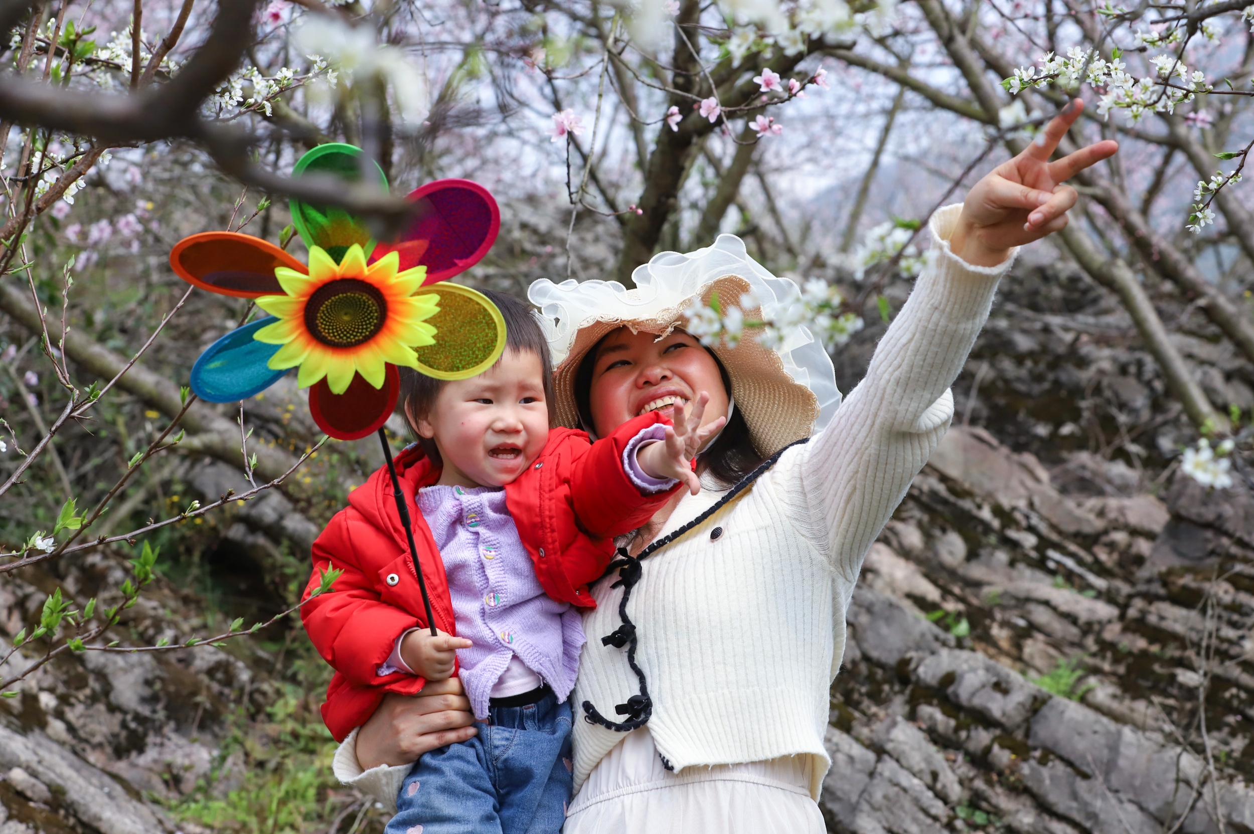 A woman and her child enjoy blooming flowers in Langxi Town, Yinjiang Tujia and Miao Autonomous County, southwest China's Guizhou Province on March 13, 2026. /Tongren Media Convergence Center