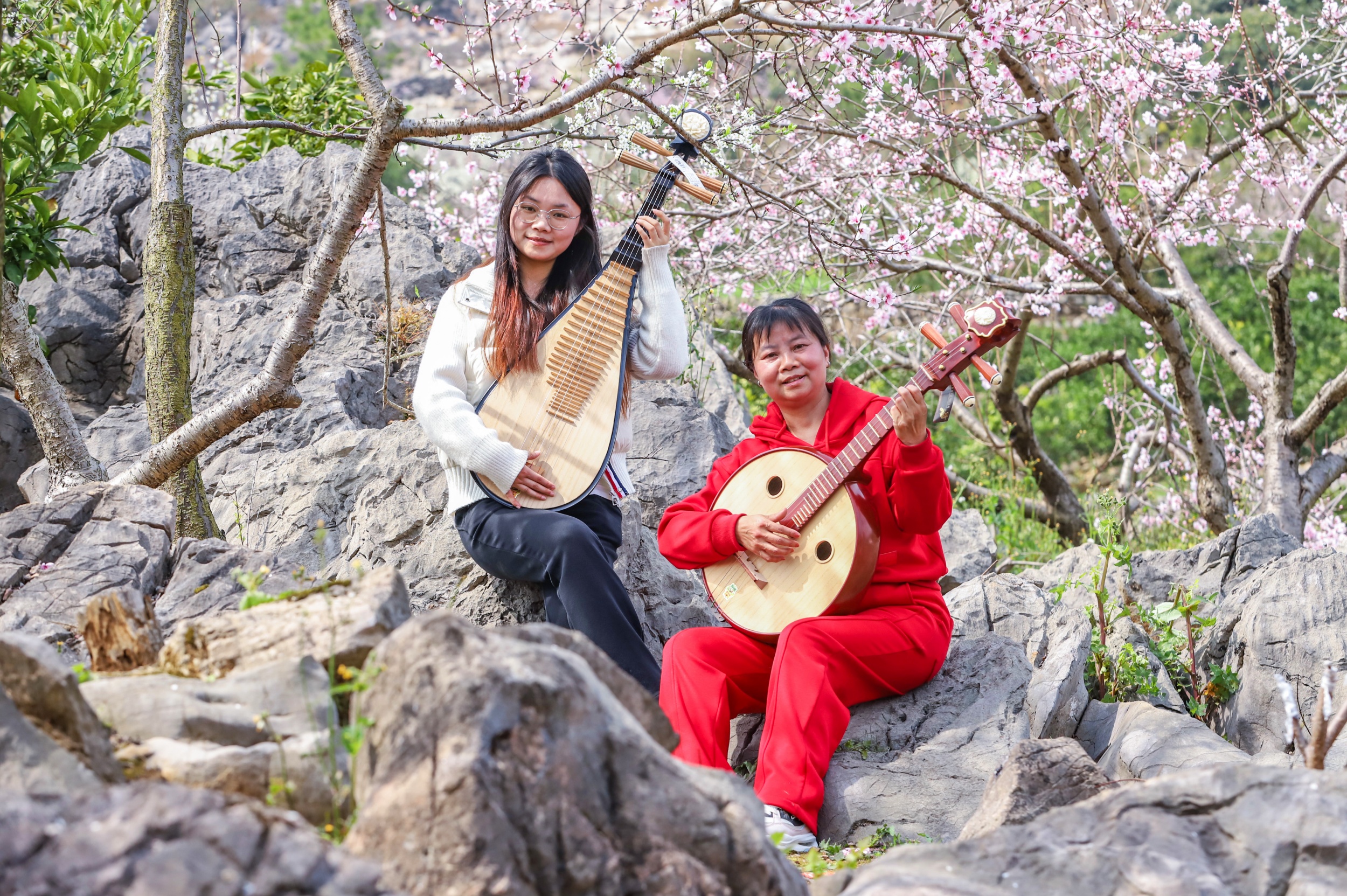 Tourists play musical instruments amid blooming flowers in Langxi Town, Yinjiang Tujia and Miao Autonomous County, southwest China's Guizhou Province on March 13, 2026. /Tongren Media Convergence Center