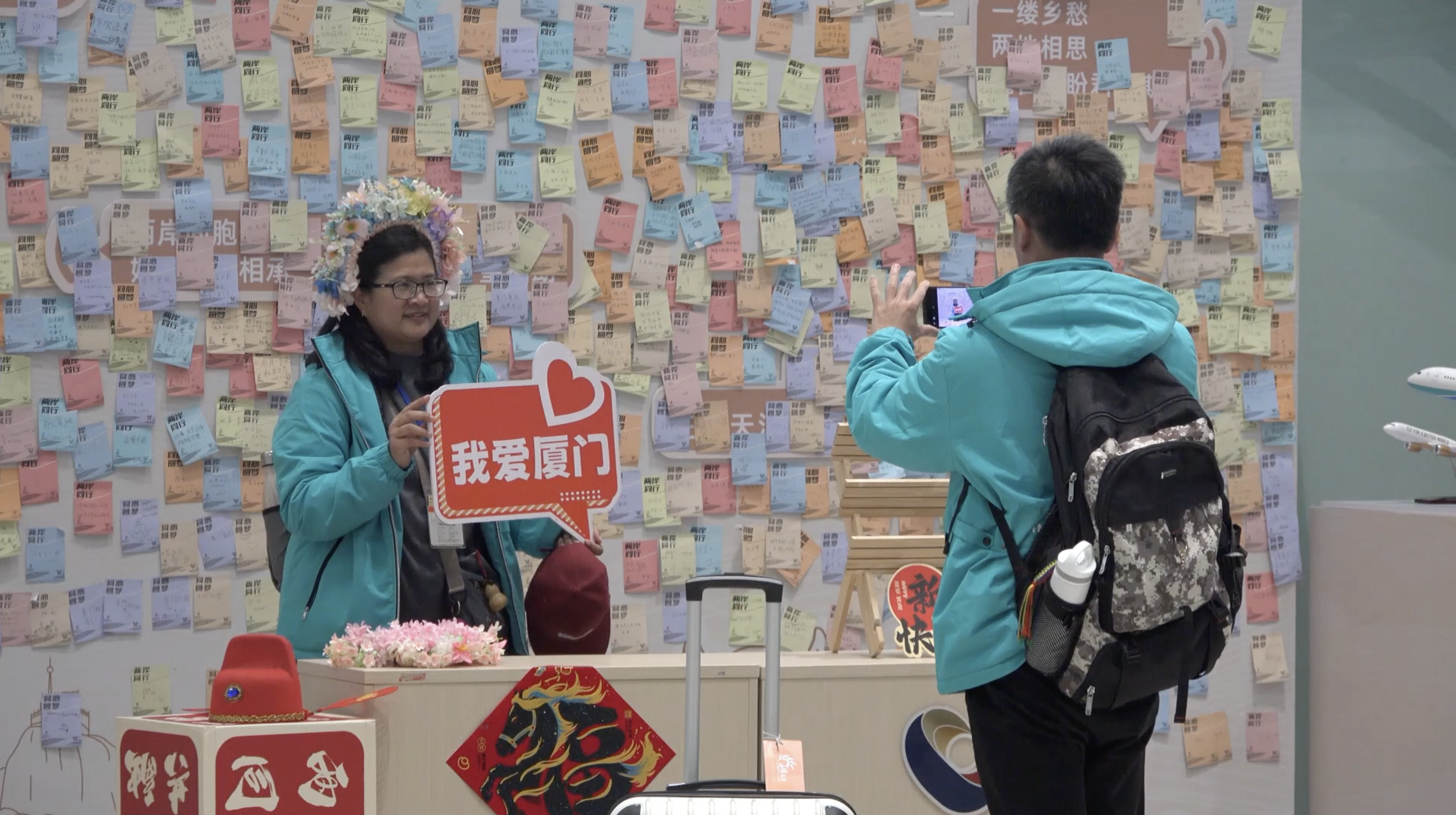 Passengers from China's Taiwan region take photos with a wishing wall as the background in the inspection station in Xiamen, southeast China's Fujian Province, March 21, 2026. /Gaoqi Border Inspection Station