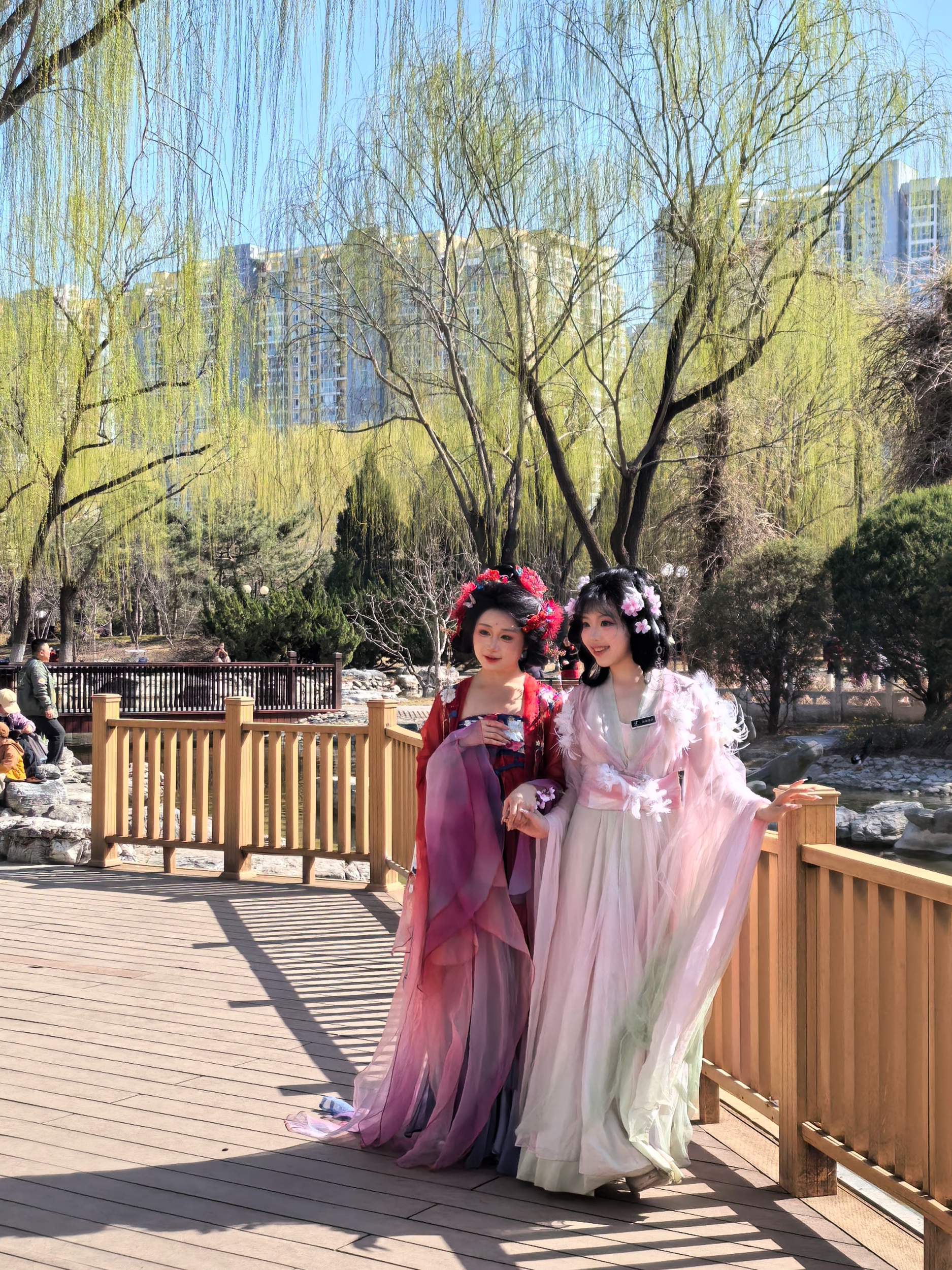 Two women in traditional Chinese attire pose for a photo at the Beijing International Sculpture Park on March 22, 2026. /CGTN