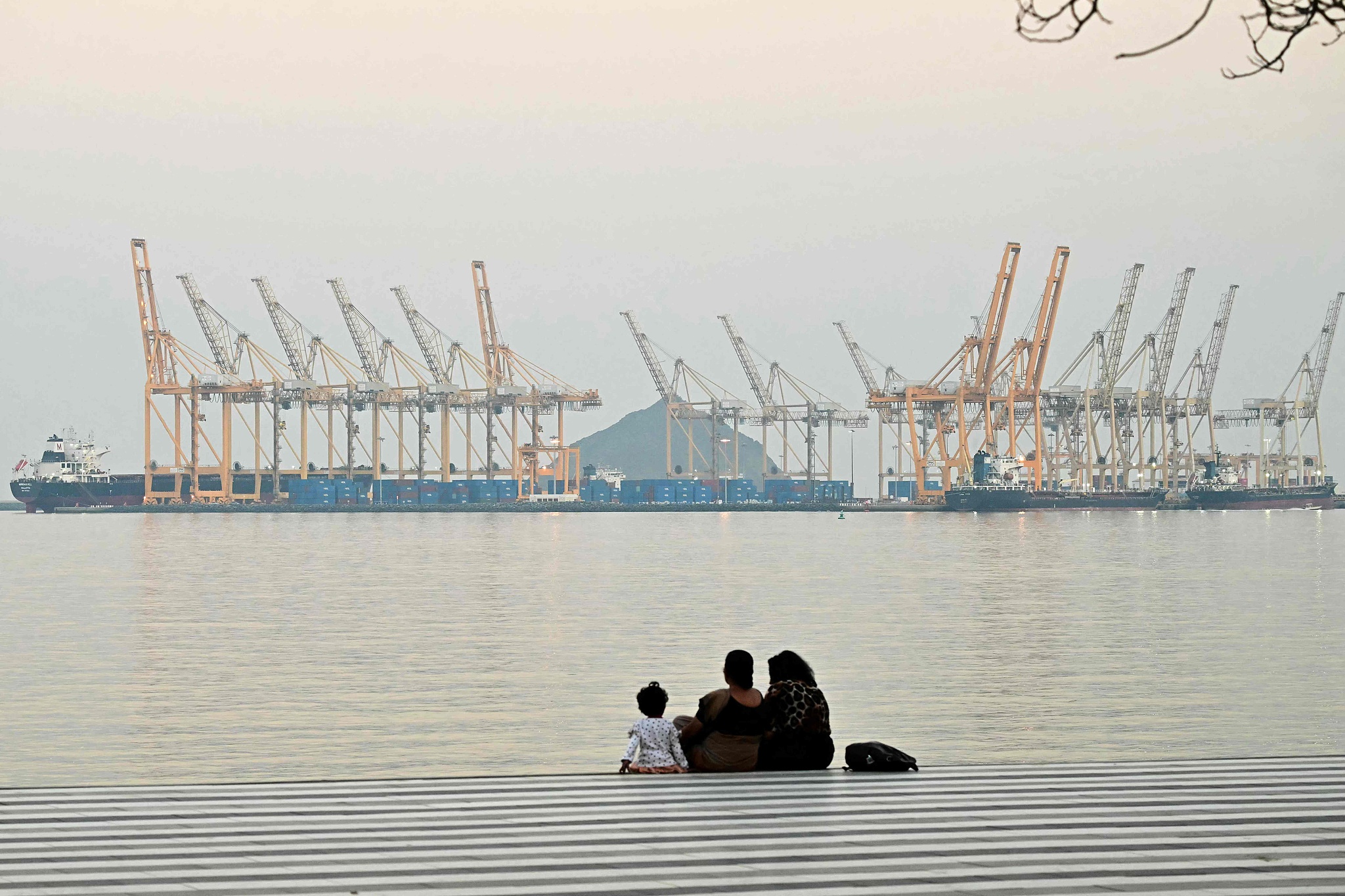 People sit against the backdrop of a dockyard in Fujairah, northern UAE, February 25, 2026. /VCG