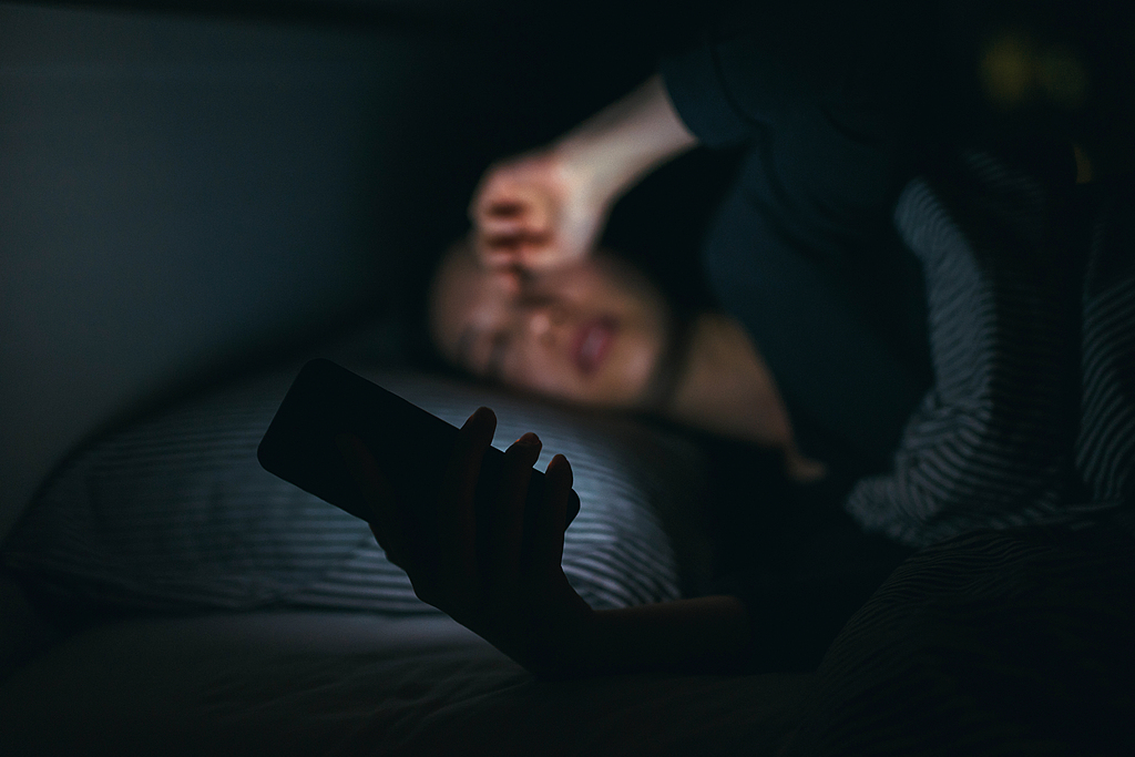 A person stays up late playing on their phone. /VCG