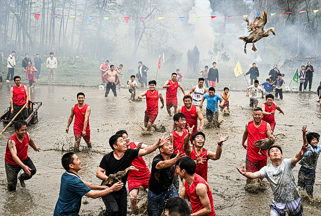 People chase a duck in muddy waters in Longyan, Fujian Province on March 2, 2026. /VCG