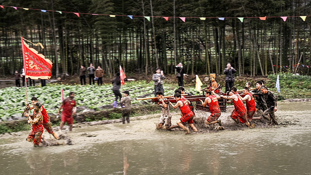 People carry a deity statue through muddy fields in Longyan, Fujian Province on March 2, 2026. /VCG