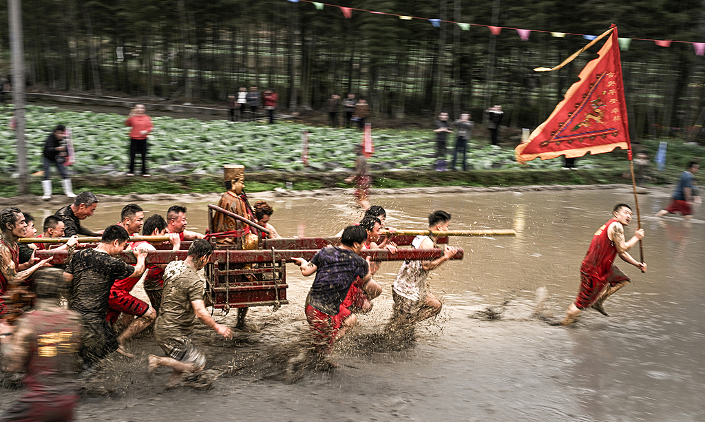 People carry a deity statue through muddy fields in Longyan, Fujian Province on March 2, 2026. /VCG