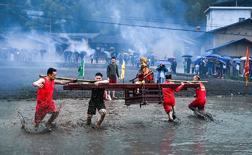 People carry a deity statue through muddy fields in Longyan, Fujian Province on March 2, 2026. /VCG