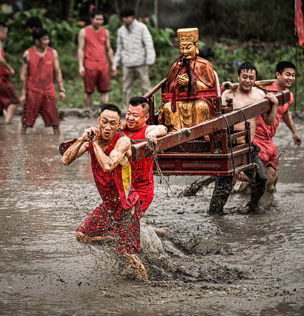 People carry a deity statue through muddy fields in Longyan, Fujian Province on March 2, 2026. /VCG